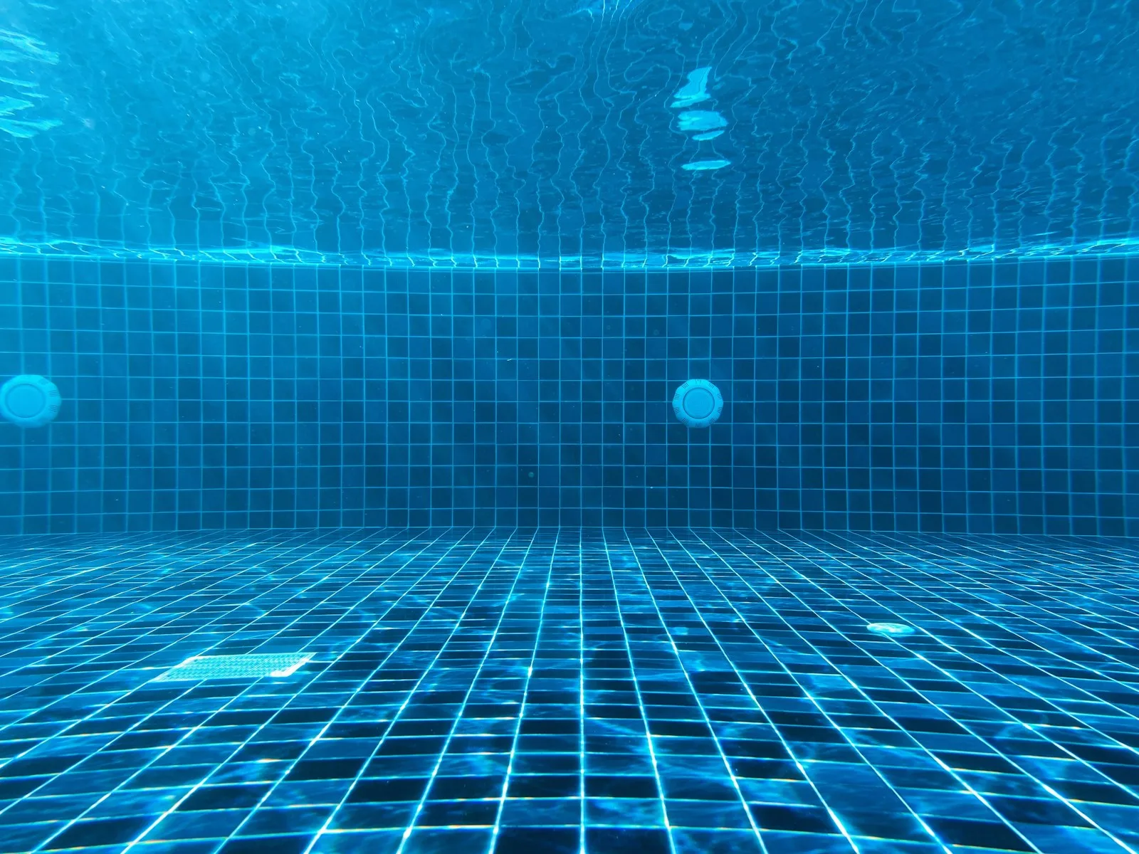 Close view of blue glass waterline tile meeting the water line of a pool