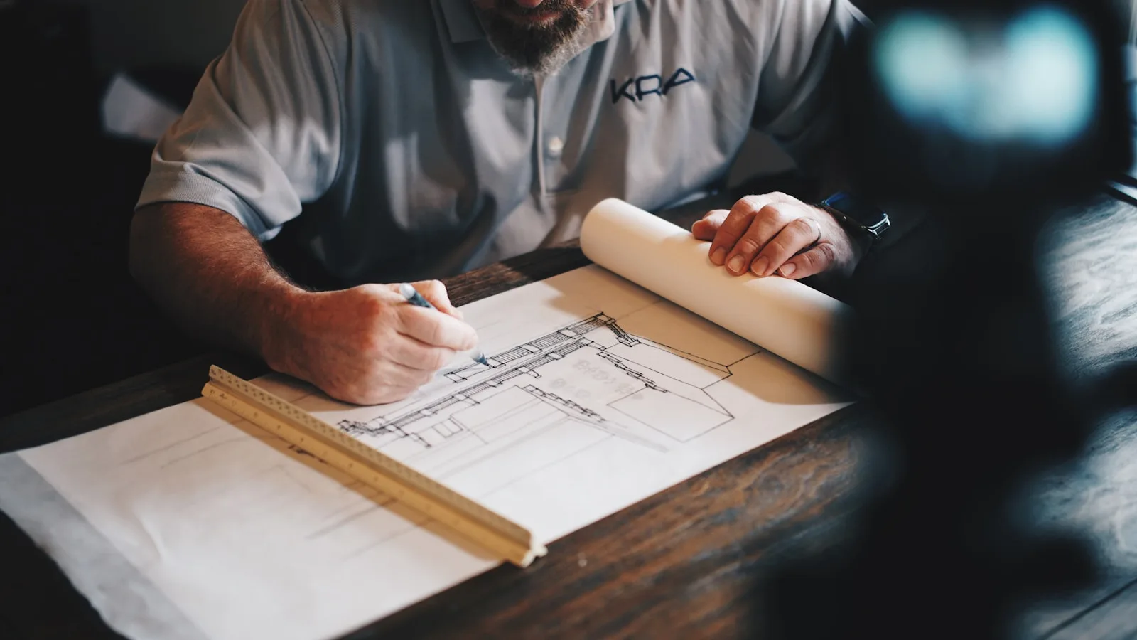 Hands drafting a construction plan at a work desk